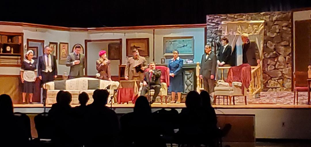 A maid, a butler, a man in a gray suit, a woman in a red cap, a man in a brown suit, a man in
       a dark gray suit sitting in a chair, a woman in a blue dress, a man in a gray suit, a woman in a black suit, and a
       man in a brown jacket