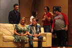 A man and a woman sit on a couch, while a man in a suit, a young woman, a man in a red Avengers
       T-shirt and a man in a Tampa Bay Buccaneers T-shirt look on behind them