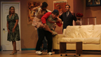 A young woman, still on the back of a man wearing a Buccaneers T-shirt, hits him, while a woman in a green dress, and
       a man in a suit look on