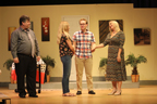 A man in a gray shirt and tie, a young woman in jeans and sandals, a young man in a plaid shirt, and a woman in a horizontally
       striped long dress